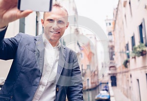 Smiling man take a selfie tourist photo on the Venice chanel background photo