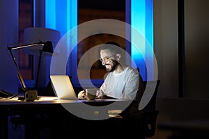 Smiling man talk using online video call in dark office stay overtime to communicate with coworkers