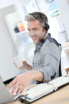 Smiling man teleworking from home with laptop photo