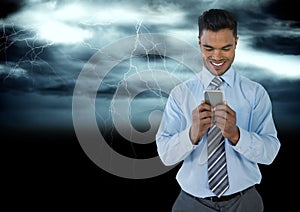 Smiling man texting in darkness with lightenings