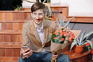 Smiling man texting while looking at the phone in his hands