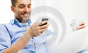 Smiling man texting message on smartphone at home