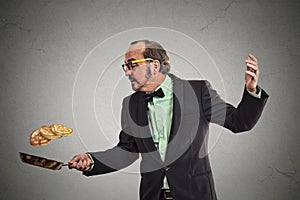 Smiling man tossing pancakes on frying pan