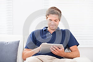 Smiling man using digital tablet on sofa