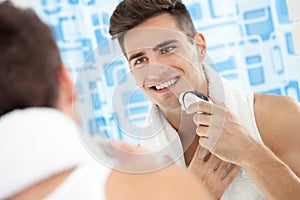 Smiling man using electric shaver