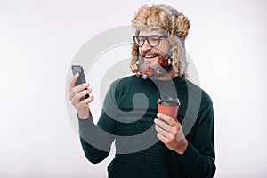 Smiling man using his smartphone and holding cup of coffee to go