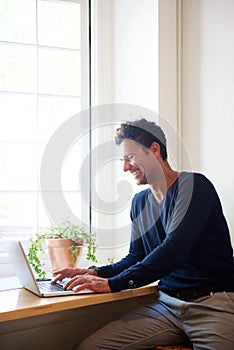 Smiling man using laptop at home