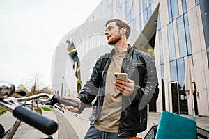 Smiling man using mobile phone while standing with bicycle outside