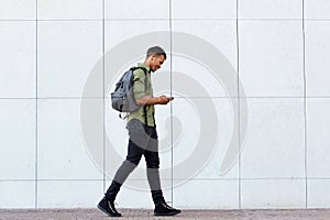 Smiling man walking with backpack smart phone and headphones