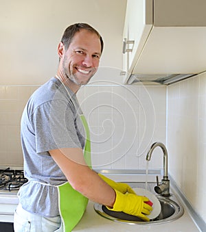 Smiling man washing dish in the kitchen