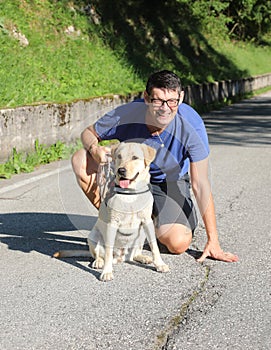 Smiling man wearing glasses while taking a walk with his dog friend labrador retriver