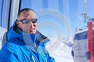 Smiling man, wearing sunglasses in ski lift cabin