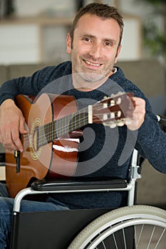 smiling man in wheelchair tuning guitar