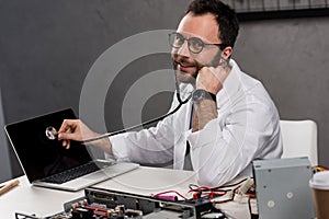 smiling man in white coat gown and stethoscope diagnose laptop