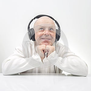 Smiling man in white sweater listening to music on portable headphones