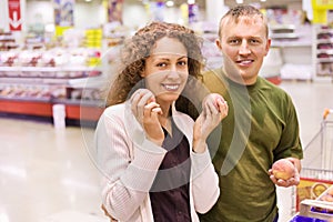 Smiling man and woman buy peaches in supermarket