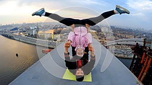 Smiling man and woman doing acrobatic yoga stunts on bridge, adrenaline junkies