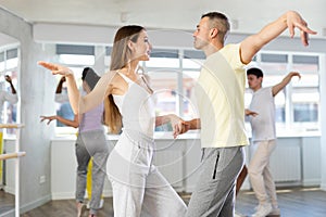 Smiling man and woman enjoying impassioned merengue at dance class