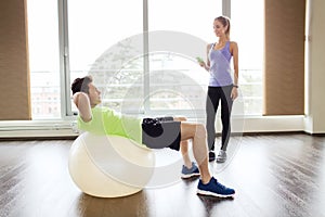 Smiling man and woman with exercise ball in gym