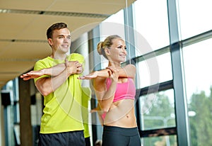 Smiling man and woman exercising in gym