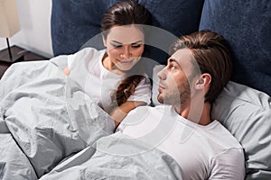 Smiling man and woman lying in bed