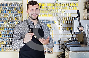 Smiling man worker showing key in workshop