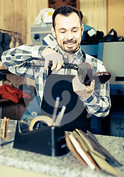 Smiling man worker working at restoring boots