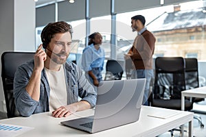Smiling man working in call center on phone with headset