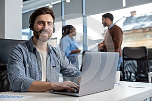 Smiling man working in call center on phone with headset