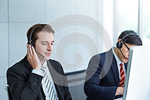 Smiling man working care customer service wearing headphone talking .with customer at call center office