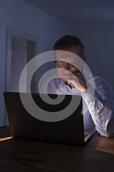 Smiling man working with laptop by night