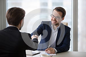 Smiling manager handshaking client applicant at meeting or job interview