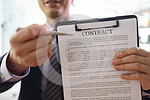 Smiling manager shows contract on clipboard in office