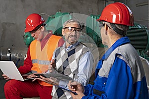 Smiling Manager Using Digital Tablet and Discussing About Production Process with Two Power Plant Workers