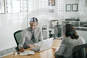 Smiling manager taking notes while conducting an office interview