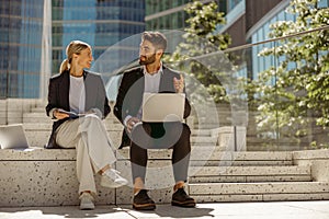 Smiling managers team working outdoor on laptop with new startup project