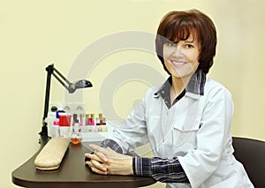 Smiling manicurist sits at table for manicure