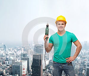 Smiling manual worker in helmet with drill machine