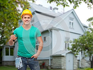 Smiling manual worker in helmet with hammer