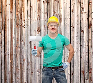 Smiling manual worker in helmet with paint roller
