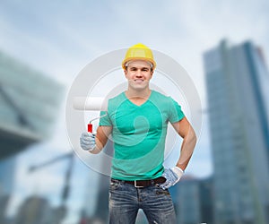 Smiling manual worker in helmet with paint roller