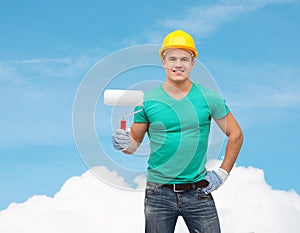 Smiling manual worker in helmet with paint roller