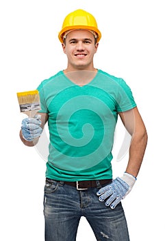 Smiling manual worker in helmet with paintbrush