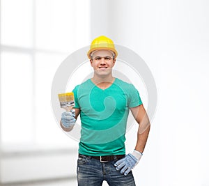 Smiling manual worker in helmet with paintbrush