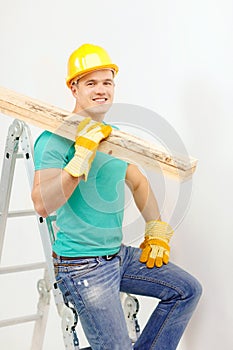 Smiling manual worker in helmet with wooden boards