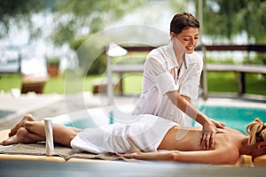 Smiling masseur is massaging a woman at spa