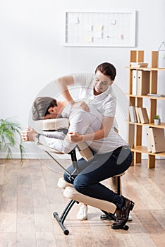 Masseuse doing arm massage for businessman