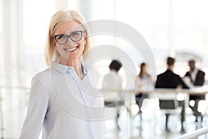 Smiling mature attractive businesswoman in glasses looking in ca