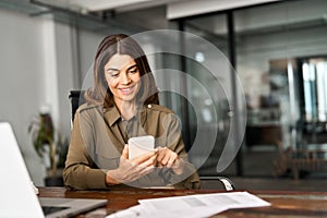 Smiling mature business woman executive using mobile phone working in office.