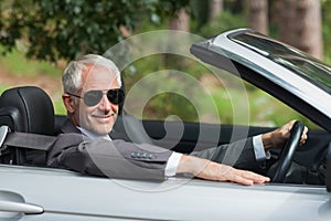 Smiling mature businessman driving classy cabriolet